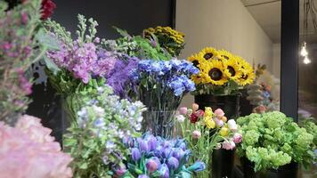 Blumen im ein Blume Geschäft. sonnig Rosen und Blau Tulpen und verschiedene farbig Blumen. video