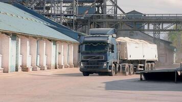 un' camion con un' trailer pieno di grano tira in un' grano e seme in lavorazione e Conservazione impresa. concetto di raccolta. video