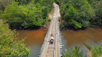 kaukasisch Frau Reiten ein Roller auf ein hölzern Brücke im Thailand. video