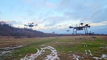 zumbido flota en un rural campo, un grande flota de drones estacionado en un rural campo durante invierno, Listo para aéreo vigilancia o agrícola tareas. video