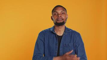 Portrait of confident person smiling on camera against orange background, posing with arms crossed in studio. Enthusiastic happy man feeling relaxed and cool, masculine figure. Camera A. video