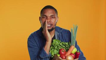 Young adult whispering his secrets about buying locally grown bio produce, advocating for sustainable lifestyle. Person recommending local farmers market with fruits and vegetables. Camera A. video