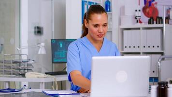 Nurse taking notes on clipboard after reading medical raports of patient from laptop. Healthcare physician in uniform, doctor assistant working in hospital checking registration, writing treatments video
