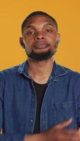 Vertical Portrait of confident person smiling on camera against orange background, posing with arms crossed in studio. Enthusiastic happy man feeling relaxed and cool, masculine figure. Camera A. video