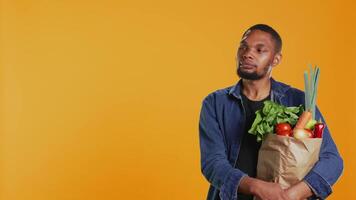 Young adult talking about organic locally grown produce in line at grocery store, recommending chemicals free fruits and vegetables. Person enjoying healthy eating and bio nutrition. Camera B. video