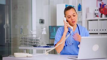 Medical assistant speaking at phone with patient analysing radiographics discussing the diagnosis, making new appointment. Healthcare physician, doctor nurse helping with telehealth communication video