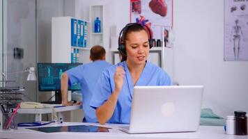 Medical assistant operator with headphone consulting patients during telehealth discussion in hospital. Healthcare physician in medicine uniform, doctor nurse helping with appointment video