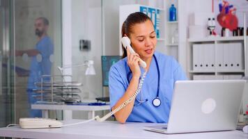 Physician nurse answering patient call by phone, looking at his radiographys, mri scan. Healthcare physician in medicine uniform, receptionist doctor assistant helping with phone concultation video