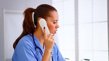 specialista medico infermiera controllo appuntamento durante telemedicina comunicazione nel Ospedale. assistenza sanitaria medico nel medicina uniforme, addetto alla reception medico assistente porzione con Telefono consultazione video