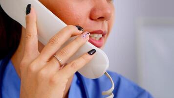 Close up of medical receptionist answering phone calls from patient in hospital making appointment. Healthcare physician in medicine uniform, doctor assistant helping with telehealth communication video
