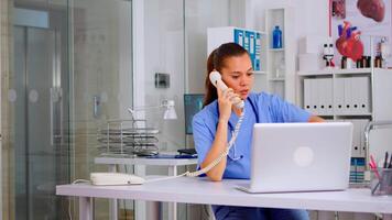 Medical practitioner talking with patient on phone from hospital office checking appointment. Health care physician in medicine uniform, receptionist doctor assistant helping with telehealth communication video