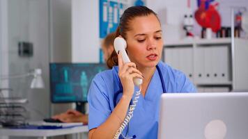 Medical practitioner answering phone calls and scheduling appointments in hospital. Healthcare physician in medicine uniform, receptionist doctor assistant helping with telehealth communication video