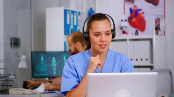 Specialist doctor nurse with headphones checking appointment during telehealth communication in hospital. Healthcare physician in medicine clinic, receptionist doctor assistant helping with concultation video