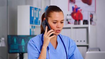 médical assistant parlant à téléphone intelligent avec médecin demander pour conseil, dactylographie sur ordinateur portable, fabrication rendez-vous soins de santé médecin dans médicament uniforme, infirmière portion avec télésanté la communication video