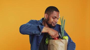 africano americano joven hombre exploración todas eco simpático Produce en estudio, comprando orgánico natural frutas y vegetales. masculino modelo utilizando un escáner a cheque Fresco comestibles. cámara una. video