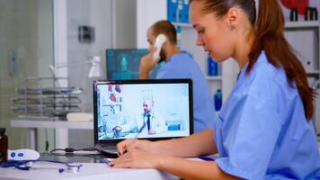 Resident physician talking to doctor on call during virtual meeting, listening medical advice and taking notes. Remote healthcare service, health conference, telemedicine online webinar. video