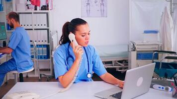 Surgeon assistant discussing with patient on phone from hospital about diagnosis, male nurse working in background. Healthcare physician, receptionist doctor helping with telehealth communication video