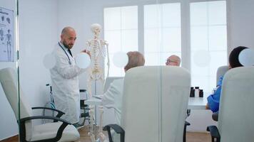 Professional physician learning colleagues body bone functionson using radiography and human skeleton anatomical model standing in hospital office. Physicians discussing about symptoms of disease video