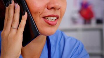 cuidados de saúde médico consultando controlo remoto pacientes usando telefone dentro hospital vestindo remédio uniforme. fechar acima do médico assistente ajudando paciente com telessaúde comunicação, diagnóstico video