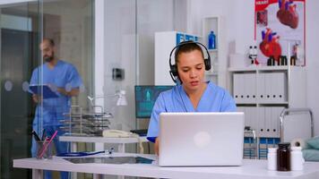 Assistant offering medical services using headphone answering calls, making appointments. hospital call center Healthcare physician in medicine clinic, receptionist doctor nurse helping with concultation video