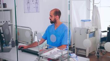 Medical man nurse writing on pc list of patient and health report, sitting in hospital office. Healthcare physician in medicine uniform typing treatments making appointments checking registration. video
