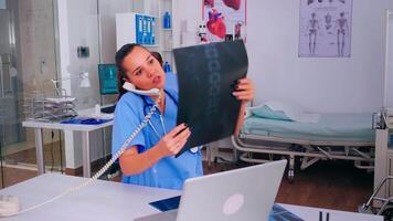 Nurse receptionist answering at hospital call checking the result of patient x-ray and diagnosing him. Healthcare physician in medicine uniform, doctor assistant helping with phone concultation video