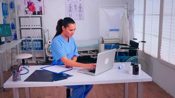 Therapist writing list of consulted patients online, making research, noting, taking useful information on clipboard. Doctor assistant in uniform working on laptop in modern hospital office. video