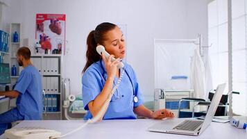 Nurse answering at hospital call checking the result of patient x-ray and diagnosing him. Healthcare physician in medicine uniform, receptionist doctor assistant helping with phone concultation video