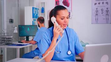 Medical team working in hospital, nurse talking on phone and colleague typing on pc. Healthcare physician in uniform, doctor nurse assistant helping with telehealth communication, remote consultation video