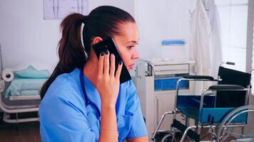 personale infermiera discutere con medico a smartphone chiede per consiglio, digitando su computer portatile, fabbricazione appuntamenti assistenza sanitaria medico nel medicina uniforme, infermiera porzione con telemedicina comunicazione video