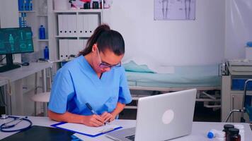 Tired nurse doctor putting off glasses resting eyes continued looking staring at pc screen. Medical physician in medicine uniform writing list of consulted, diagnosed patients, making research. video