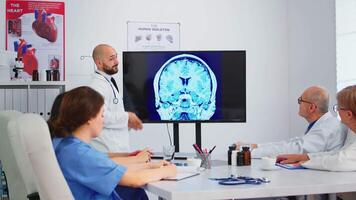 kvalifierad skäggig huvud läkare förklara hjärna strukturera för hans koncentrerad kollegor under medicinsk möte. grupp av doktorer diskuterar diagnos handla om behandling av patienter i sjukhus styrelserum video