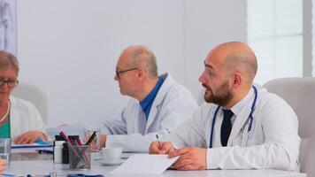 lluvia de ideas trabajo en equipo de medicos resolviendo problemas de pacientes en moderno hospital reunión habitación teniendo médico conferencia. equipo de doctores hablando acerca de síntomas de enfermedad en clínica oficina. video