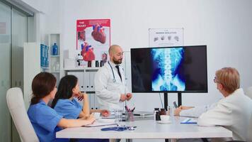 Doctors in white coats sitting in hospital boardroom working with digital x-ray spin image discussing symptoms of disease for further treatment. Practical work of interns, medical examination video