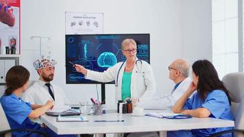 anziano donna neurologo analizzando cervello funzioni utilizzando alto Tech nel medico conferenza camera, medico analisi nuovo innovazione. medico studiando diagnosi per trattamento di pazienti Lavorando nel sala del consiglio video