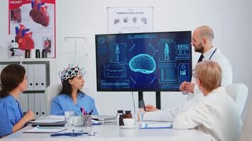 équipe de médecins en cours d'analyse cerveau les fonctions en utilisant haute technologie dans médical conférence chambre, assistant essai Nouveau innovation. médical en train d'étudier diagnostic pour traitement de les patients travail dans hôpital salle de réunion video