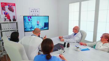 Medicine staff having videoconference of hospital team with expert doctor using internet during online meeting. Doctors talking with therapist for expertise in conference office. video