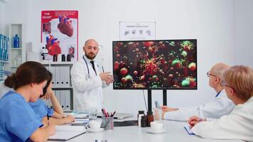 Specialist medic explaining virus development on digital screen in front of coworkers pointing on monitor in hospital office during brainstorming. Team of physicians analysing diagnosis of patients video