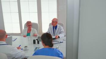 sjukvård arbetare har möte i sjukhus konferens rum handla om symptom av patienter analyserar röntgen. klinik expert- terapeut talande med kollegor handla om sjukdom, medicin professionell video