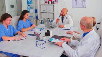 Academic meeting of expert doctors discussing about symptoms of disease working in hospital conference room. Clinic expert therapist talking with colleagues about treatment of patients video