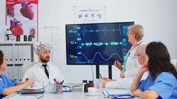 anziano donna ricercatore utilizzando medico alto Tech analizzando cervello impulso nel conferenza camera, assistente analisi nuovo innovazione. medici studiando diagnosi per trattamento di pazienti Lavorando nel ospedale video