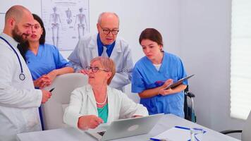Medical practitoner working on laptop during briefing with coworkers and nurse taking notes. Clinic expert therapist talking with colleagues about disease, medicine professional video