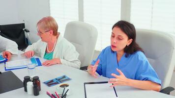 ervaren volwassen artsen uitleggen geduldig diagnose naar jong medisch artsen gedurende conferentie. kliniek deskundige therapeut pratend met collega's over ziekte, geneeskunde professioneel. video