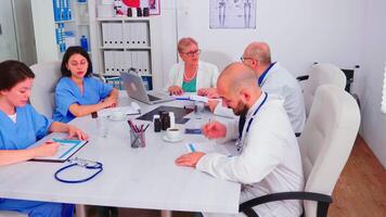 médico practicante comprobación lista con pacientes en portapapeles hablando con médico durante sala del consejo reunión. clínica experto terapeuta que se discute con colegas acerca de enfermedad, medicina profesional. video