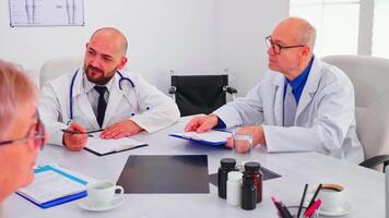 dokter Holding presentatie over symptomen van patiënten in voorkant van medisch team planning Onderzoek stappen. medisch team hebben conferentie bespreken over mensen ziekte zittend in ziekenhuis kantoor video