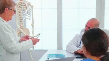 weiblich Radiologe Arzt halten Präsentation mit Skelett im Vorderseite von medizinisch Mitarbeiter. Klinik Experte Therapeut reden mit Kollegen Über Krankheit, Medizin Fachmann Arbeiten im Sitzungssaal video