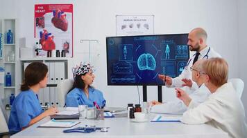 Neurologist showing new inovation to colleagues discussing brain functions using high tech in medical boardroom. Medic studying diagnosis of patients working in hospital conference room video