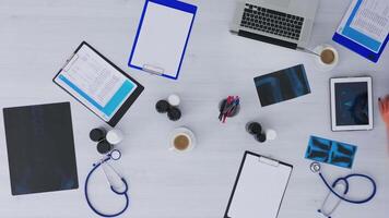 Top view of medical student learning using digital program on tablet with x-ray, clipboards and medical equipment all around. Studying in hospital office, copy space, flat lay concept video