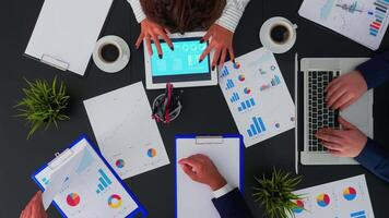 Top view of business people having meeting analysing financial statistics graphs planning next project using digital devices on corporate office. Teamwork brainstorming on copy space, flat lay concept video