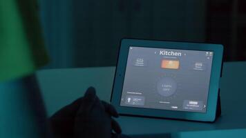 Mann Sitzung beim Schreibtisch im Clever Zuhause Automatisierung System reden zu Stimme Assistent auf Tablette zu Wende auf Beleuchtung von Haus. männlich mit intelligent Software, Gadget platziert auf Küche Tabelle steuern Licht video
